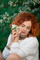 beautiful red-haired girl near a flowering tree