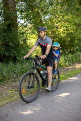 Obraz premium Father, riding a bike with child seat and little toddler boy riding with him in the seat, holiday