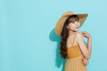 リゾートファッションをした若い女性の青背景のポートレート