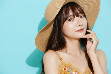リゾートファッションをした若い女性の青背景のポートレート