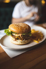 Man eating a burger. Close-up of a burger on the table. Fast food. Man eating a cheeseburger. Unhealthy food.