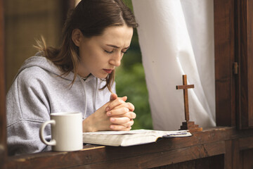 The girl reads the Bible and prays. Prayer process. Faith and hope. The process of praying to God....