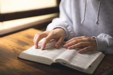 Close-up of hands on the Bible. The process of studying the Bible. Prayer and worship of God. Study of the Holy Scriptures. Studying in theological seminary. Theology.