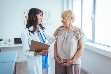 Happy senior woman visiting doctor and listening to her advice during appointment. Nurse Showing...