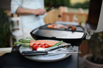 Vegetables on plate prepared for grilling during weekend barbecue in yard, outdoor.