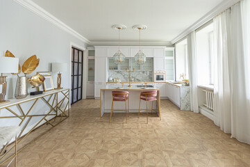 a close view of the white stylish kitchen with a cooking island in the luxurious interior of a modern apartment in light colors with stylish furniture.