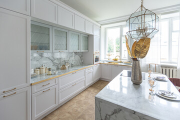 a close view of the white stylish kitchen with a cooking island in the luxurious interior of a...