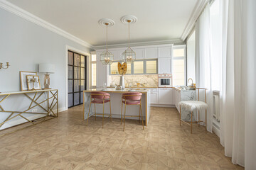 a close view of the white stylish kitchen with a cooking island in the luxurious interior of a modern apartment in light colors with stylish furniture.