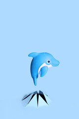 Rubber dolphin toy pops out of torn blue cardboard paper.