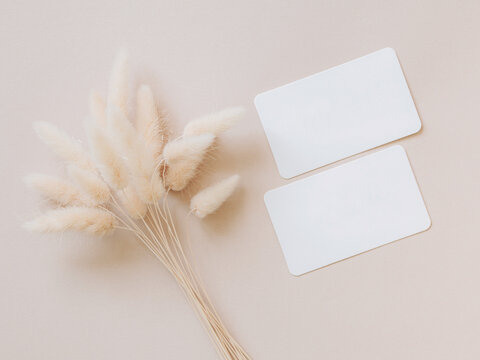 Two blank white cards and bouquet of dried flowers on beige background top view