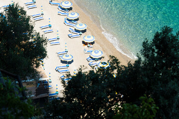 View from above, stunning aerial view of some beach umbrellas on a beautiful beach bathed by a crystal clear water. Amalfi Coast, Italy.