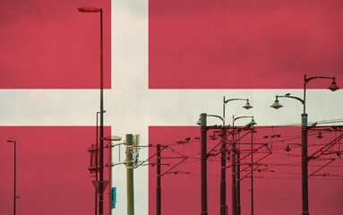 Denmark flag with tram connecting on electric line with blue sky as background, electric railway train and power supply lines, cables connections and metal pole overhead catenary wire