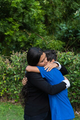 Two happy siblings laughing and hugging in a park