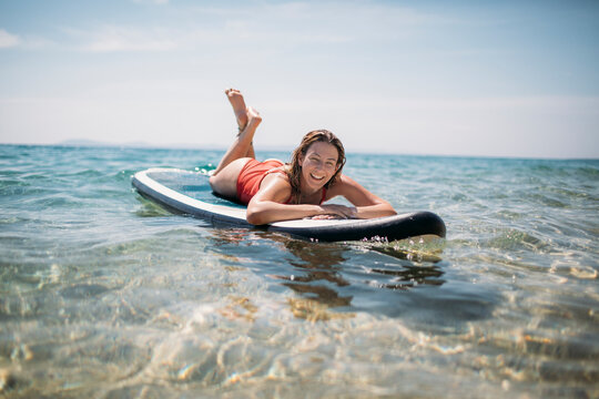 Smiling woman enjoy beach time floating on paddle board