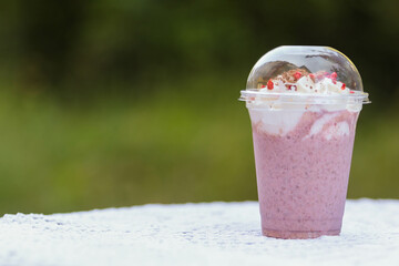 Cool milkshake with raspberries in a plastic cup