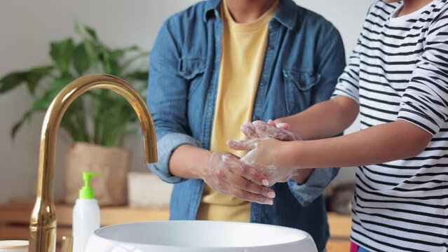 Closeup View Of Mother, Child Are Washing Hands And Standing In Bright Bathroom At Home Spbi. 4k Young African Woman, Girl Clean Skin Of Arms And Use Liquid Soap, Stand By Sink In Interior. Modern Mom