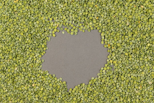 Dry split peas. Green uncooked beans against a gray background. Free space for text and design elements in the center. Top view.