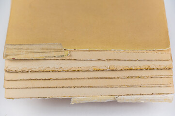 An old tattered book against a neutral background. Brown pages. Softcover. Torn text blocks. Selective focus.