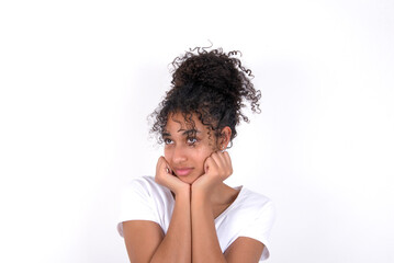 Fototapeta na wymiar Portrait of sad Young beautiful girl with afro hairstyle wearing white t-shirt over white background hands face look empty space