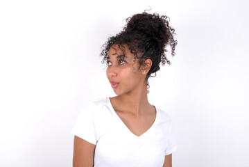 Shocked Young beautiful girl with afro hairstyle wearing white t-shirt over white background look empty space with open mouth screaming: Oh My God! I can't believe this.