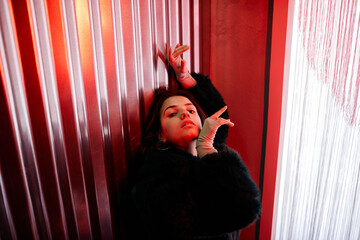 Fototapeta na wymiar High angle portrait of sensual young woman dancing vogue style in red neon light and looking at camera, copy space