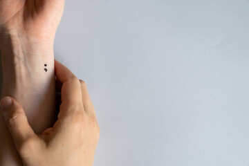 Depression and mental health concept - semicolon tattoo on wrist, 