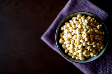Top view of soy beans in black ceramic bowl on dark woodle table. Soaked japanese soy beans