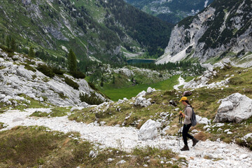 Fototapeta na wymiar Mid Adult Woman Descending Alpine Trail of Mount Krn in Direction of Lake of Krn - Triglav National Park Slovenia