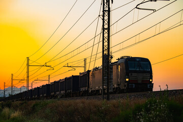 Fototapeta na wymiar Freight train running on the tracks at sunset