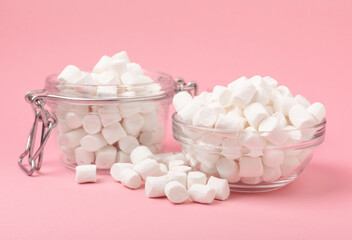 Marshmallows in a glass bowl and a jar on a pink background.Sweets and snacks for a snack.Chewy candy close-up.Copy space.Place for text.