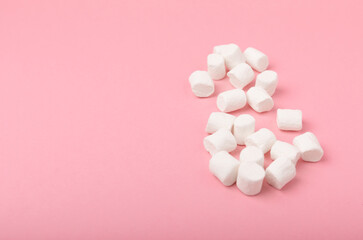 Loose marshmallows on a pink background. White marshmallow flat lay. Sweets and snacks for a snack. Chewing candies close-up. Copy space. Place for text. Winter food concept.