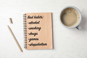 Notebook with list of bad habits and cup of coffee on white wooden table, flat lay