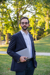 portrait of a stylish caucasian businessman posing holding his laptop and looking away