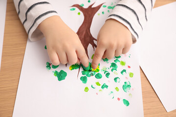 Little child painting with fingers at wooden table , closeup