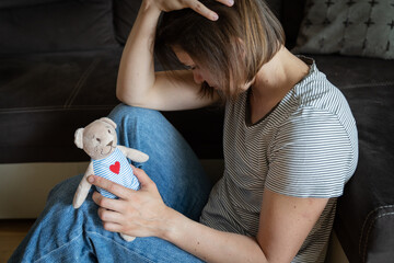 Perinatal loss reproductive chalenge concept - female holding a teddy bear toy - obrazy, fototapety, plakaty