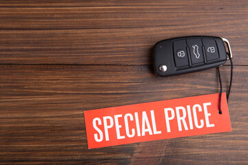 Car sale concept. Special price! Vehicle security key with tag on the wooden background