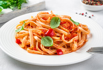 Italian pasta with tomatoes and basil close-up on a light gray background. Side view. Italian cuisine.