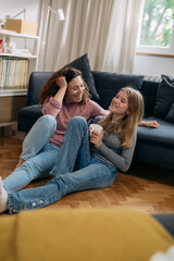 mother and teenager daughter talking at home. sitting on floor in living room