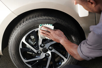 Close-up image driver cleaning aluminum wheels with soft cloth to make it shine