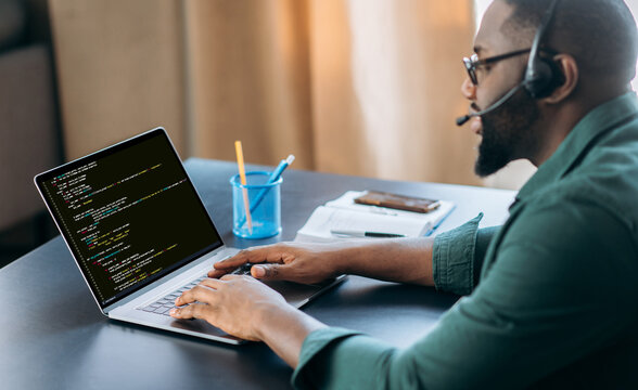 Side view of successful african american IT specialist, programmer, sits in a modern office, working on the development of a website, application, writing codes and data code. Software concept