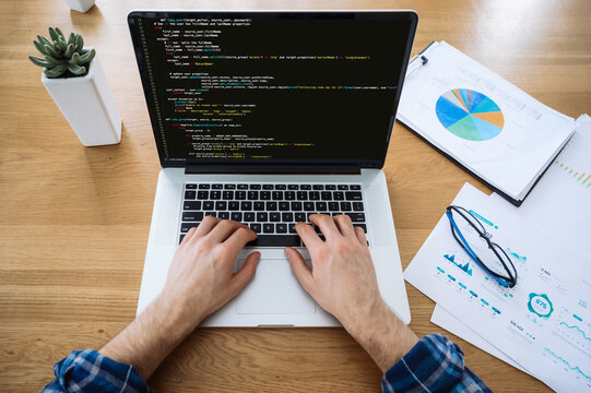 Software concept. Top view of male hands on laptop keyboard, IT specialist, programmer, uses laptop, typing code, working on the development of a website, application, writing codes and data code