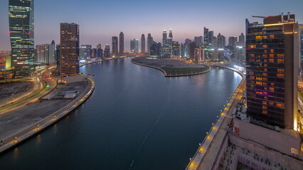 Fototapeta premium Cityscape of skyscrapers in Dubai Business Bay with water canal aerial day to night timelapse