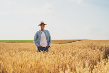Naklejka na ściany i meble Happy farmer is standing in his growing wheat field. 