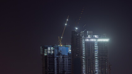 Cranes working on constraction site works of new skyscrapers night timelapse