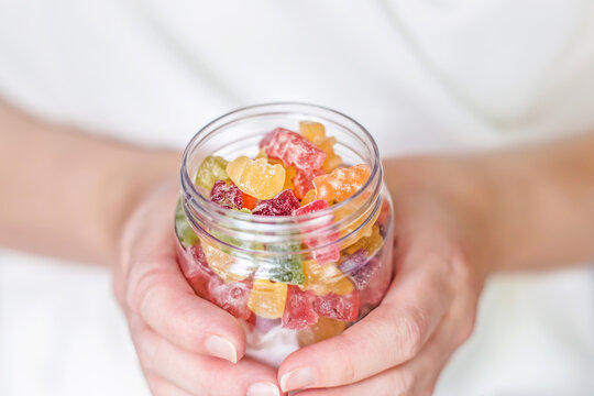 Female hands holding a glass jar of gummy bears close up. Childrens sweets.