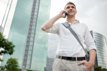 Portrait of young man in white shirt calling to taxi service to order car