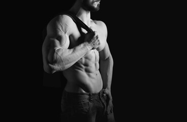 Naklejka na ściany i meble Portrait of shirtless muscular man in a jeans. Young male hunk showing his perfect body and muscles on black background