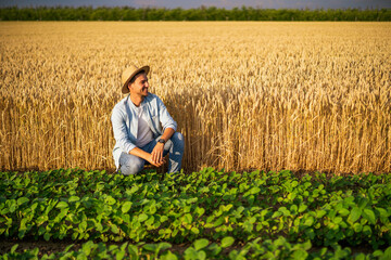 Naklejka na ściany i meble Happy farmer enjoys in his growing wheat and soybean field.