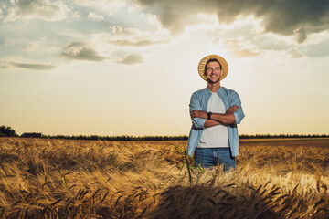 Happy farmer is standing in his growing barley field.