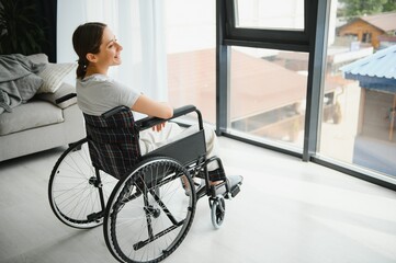 Fototapeta na wymiar woman looking away while sitting in wheelchair at home